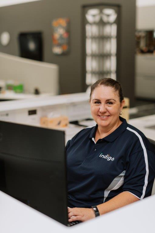 Professional woman with dark hair, smiling at a computer