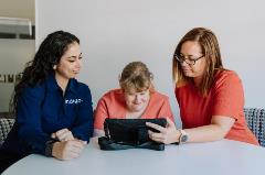 OT-Customer_Support person_AAC Female Indigo staff sitting with two females using iPad in a room