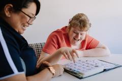 Female Indigo staff sitting with female customer using PODD book in a room