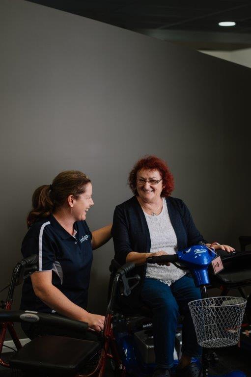 female Indigo staff kneeling next to female customer on blue scooter