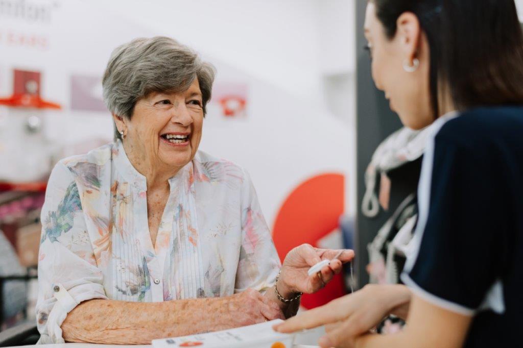 Mature Aged female Smiling holding a Personal Alarm with Staff in Abstract