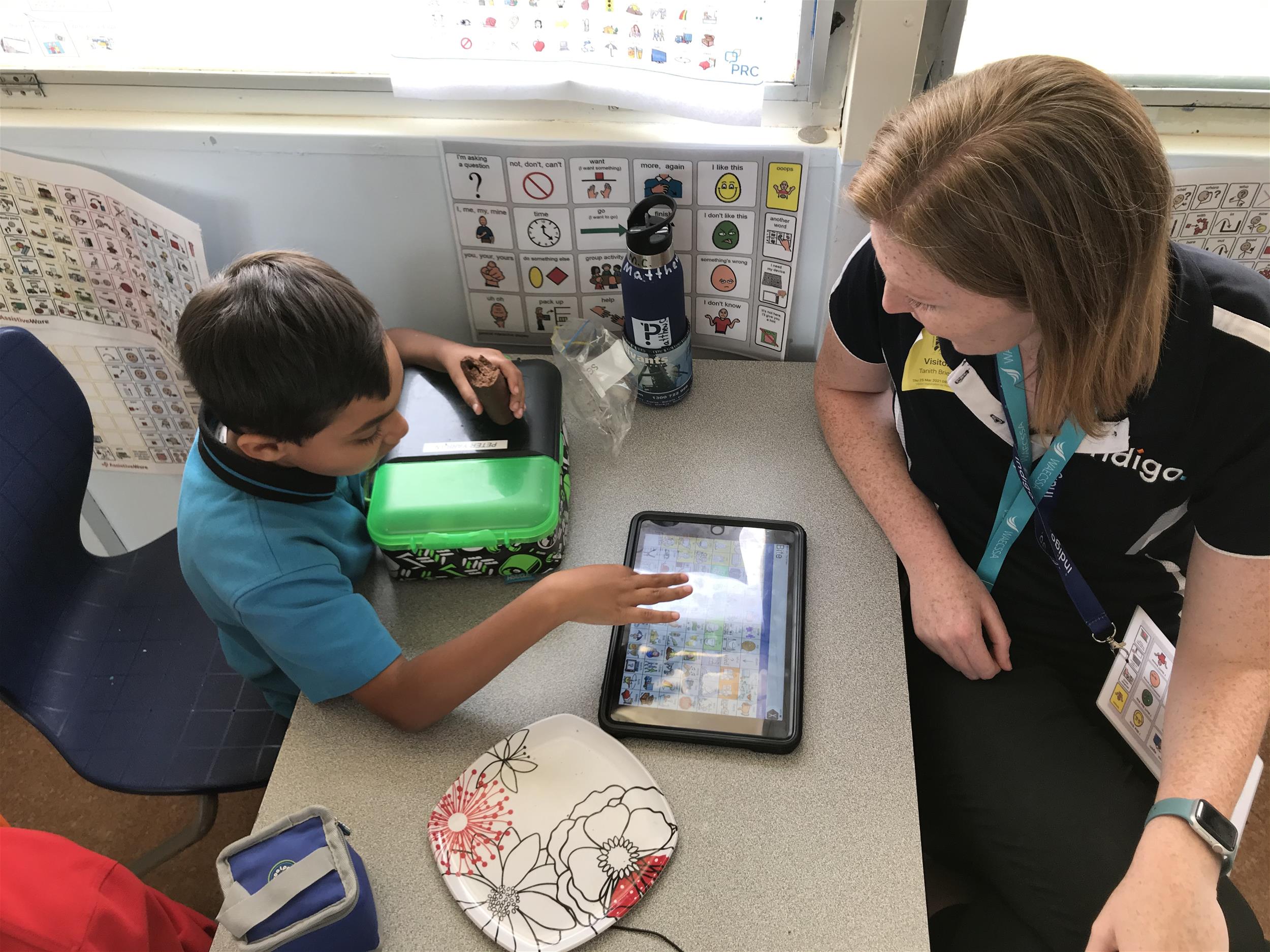 2021_OConnor_GabrielTanith05 Young boy pointing at PODD book pic that's held by female Indigo staff